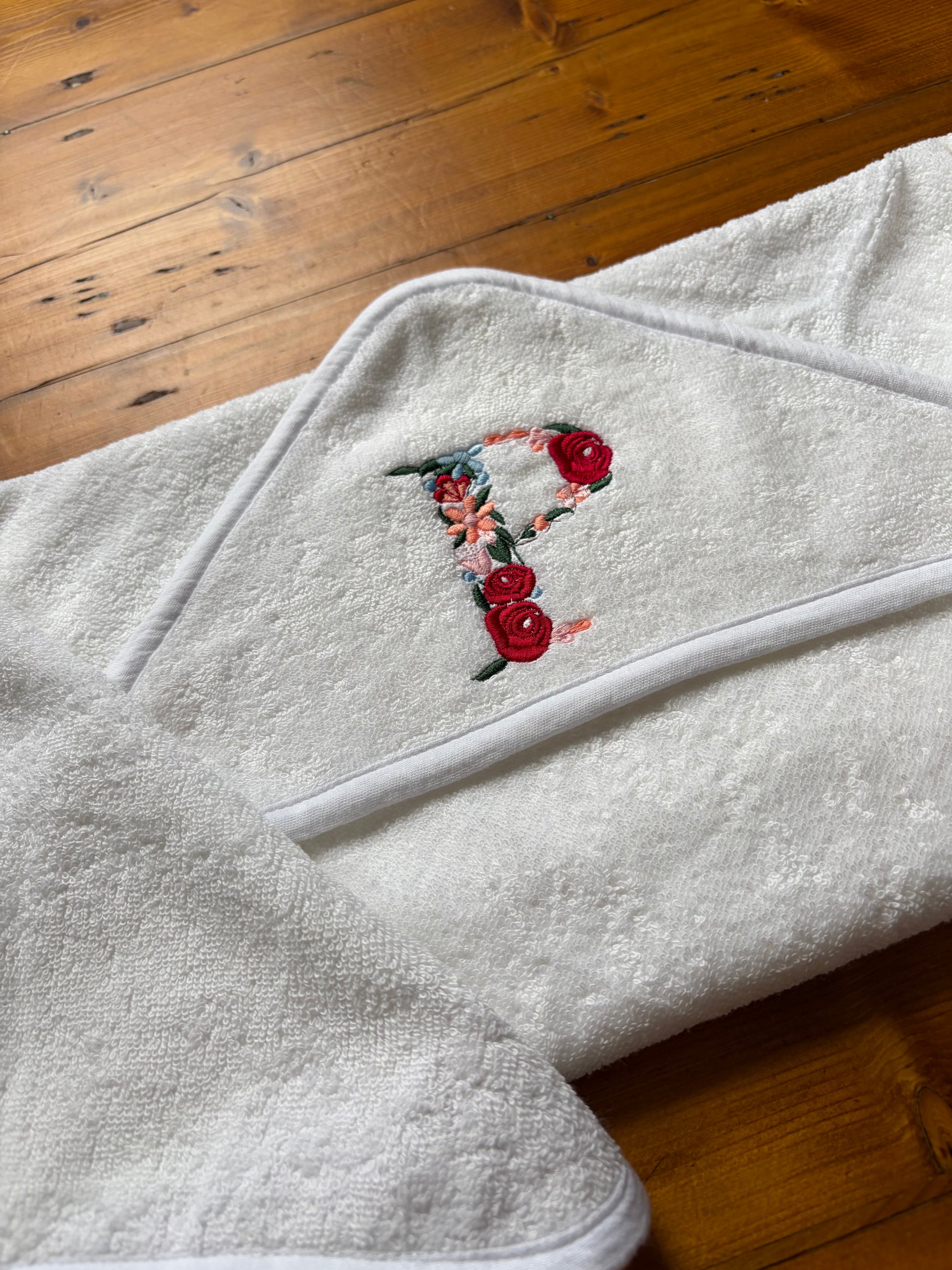 White personalised hooded baby towel with floral letter P embroidery featuring our Rose Floral font 